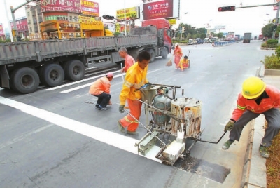 工人在用手推熱熔劃線(xiàn)機(jī)施劃標(biāo)線(xiàn)