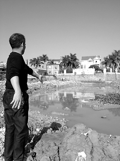 村民指著“被拓寬”的池塘。