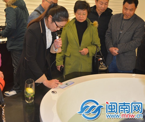 ()輝煌水暖的工作人員演示操作智能化的浴缸