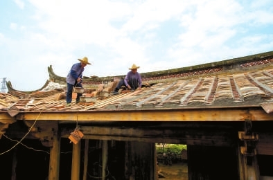 工人在鋪設孝友第屋頂上的瓦片。