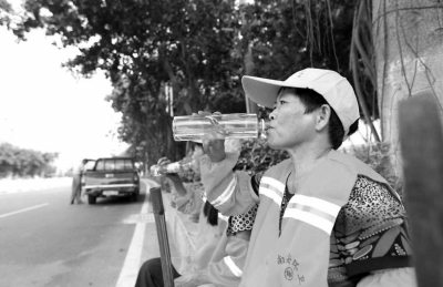 酷暑難耐，清潔工在小憩時(shí)為自己補(bǔ)充水分。本報(bào)記者